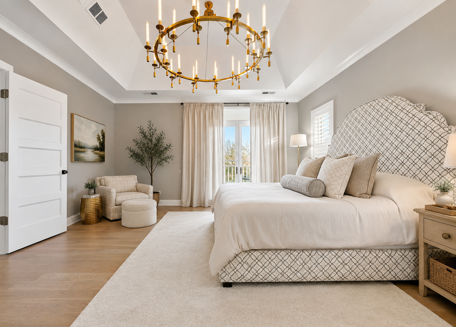 Primary bedroom with gold chandelier, patterned upholstered headboard, and warm neutral palette